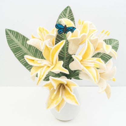 Decorative arrangement of yellow flowers and green leaves with a blue butterfly on a white background