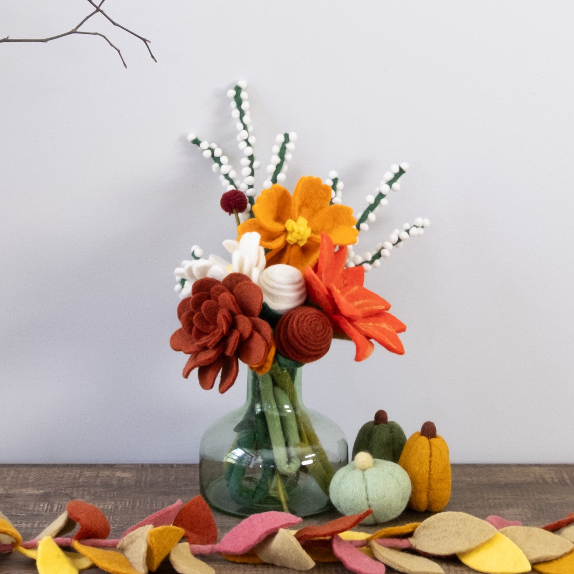 Wooden console table with decorative items including a vase of flowers, pumpkins, and autumn leaves on a plain background.